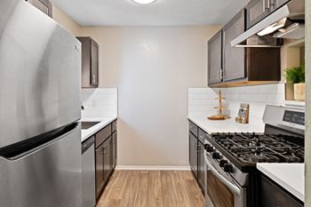 an empty kitchen with stainless steel appliances and white countertops at 300 Riverside Apartments, Georgia, 30168